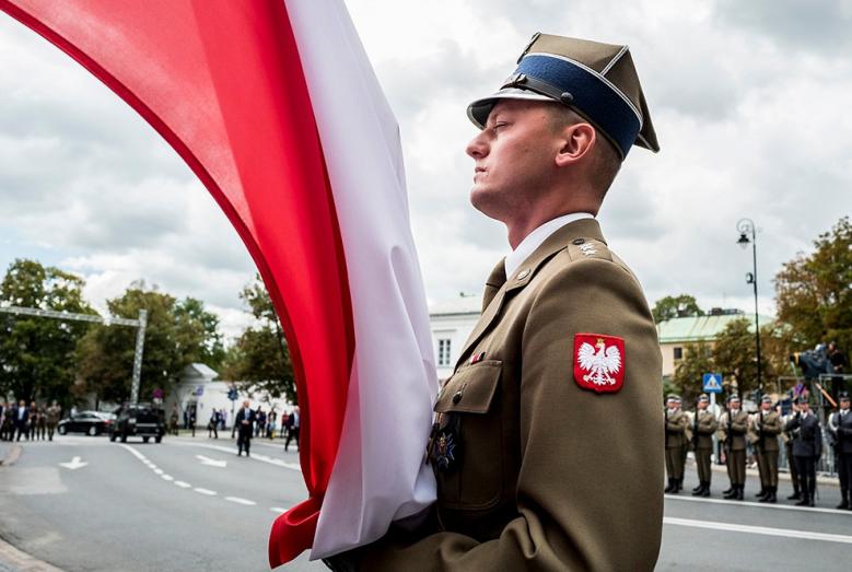 żołnierz Wojska Polskiego przy polskiej fladze