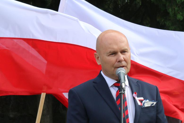 Burmistrz Slawomir Kowalewski na tle biało-czerwonych flag
