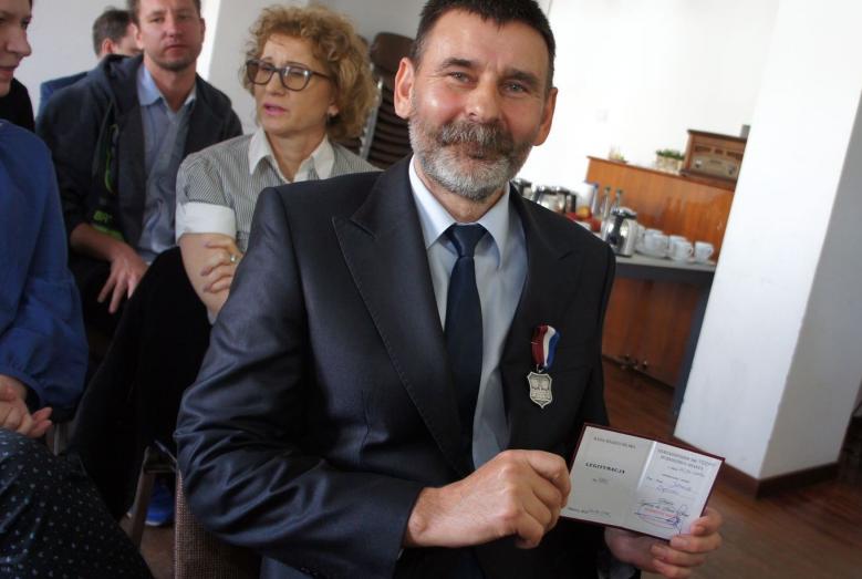 Janusz Dębski z medalem Zasłużony dla Miasta Mława i poświadczającą jego przyznanie legitymacją