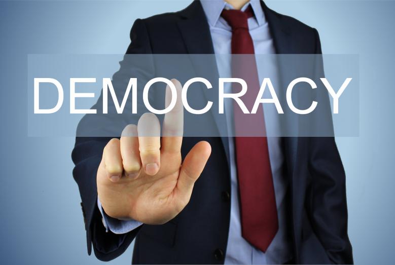 człowiek wskazujący palcem na napis DEMOCRACY