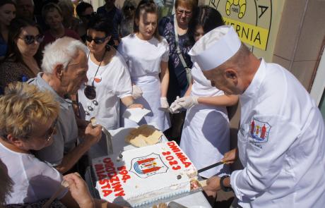 Burmistrz Sławomir Kowalewski częstuje uczestników Dni Mławy tortem urodzinowym miasta.