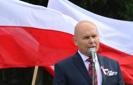 Burmistrz Slawomir Kowalewski na tle biało-czerwonych flag