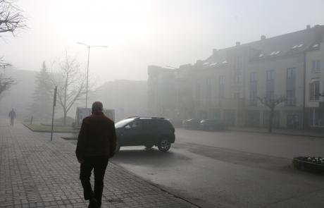 Zamglona ulica, mężczyzna na chodniku widziany z tyłu