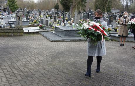 Składanie kwiatów i zniczy pod pomnikiem na cmentarzu parafialnym