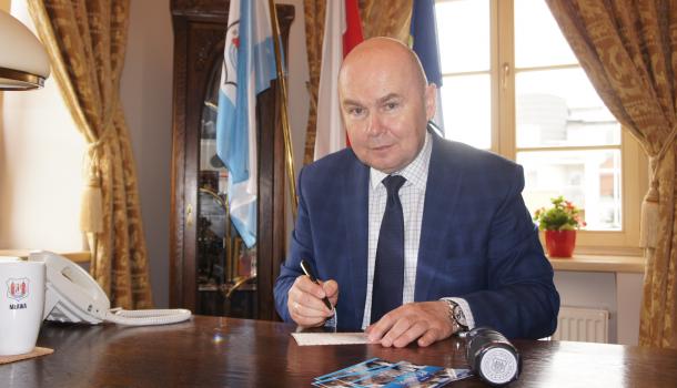 Burmistrz Sławomir Kowalewski podpisuje widokówki