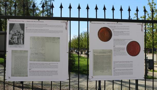 Dwie plansze wystawy na ogrodzeniu parku