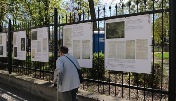 Cztery plansze wystawy na ogrodzeniu parku, przy ogrodzeniu przechodzień
