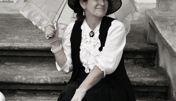 Kobieta rekonstruktorka z parasolem siedząca na schodach